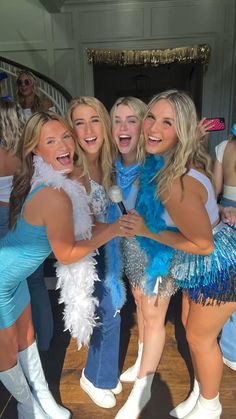 four women dressed in blue and silver posing for the camera with their arms around each other