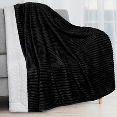 a black and white blanket sitting on top of a couch next to a gray chair