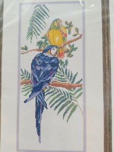 a cross stitch picture of a blue bird on a tree branch