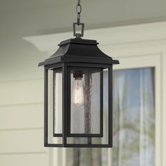 an outdoor light hanging from the side of a house with a window in the background