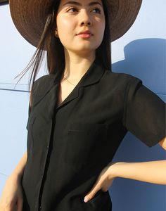 Vintage womens shirt in black. Collared. V neckline. Short sleeve. Double chest pockets. Semi sheer. Size S/M, UK 6-12 / EU 34-40 Measurements - 38"/ 97cm bust - 9" / 23cm sleeve length - 22" / 56cm length. Condition - Excellent Material - Silk mix. Sustainability - Vintage Handpicked, repaired and ready to wear. This is an original vintage item, not new and minor signs of wear & age are expected, we will highlight any major flaws. Model is a UK 6/8 and is 5'7" tall Summer V-neck Shirt With Pockets, Classic V-neck Tops With Pockets, V-neck Shirt With Pockets For Work, V-neck Workwear Shirt With Pockets, Trendy Summer Blouse With Pockets, Black Tops With Pockets And Lapel Collar, Black Top With Lapel Collar And Pockets, Black Top With Pockets And Lapel Collar, Summer Office Blouse With Pockets