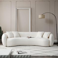 a large white couch sitting on top of a floor next to a lamp and table