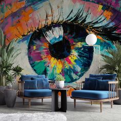 an eye painted on the side of a wall next to two chairs and a table