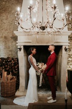 a bride and groom standing in front of a fireplace