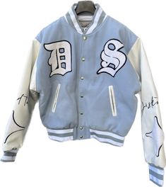 A varsity bomber jacket is a type of outerwear that is typically associated with American collegiate and sports culture. It draws inspiration from traditional letterman jackets worn by varsity athletes. The jacket is characterized by its casual and athletic design, often featuring a snap-button front closure, ribbed collar, cuffs, and waistband. The varsity bomber jacket is usually made of durable materials such as wool or nylon, providing warmth and protection from the elements. The body of the Long Sleeve Varsity Jacket For Sports Season Streetwear, Blue Cotton Varsity Jacket For Streetwear, Blue Hip Hop Outerwear For Streetwear, Baseball Collar Track Jacket For Streetwear, Blue Collegiate Varsity Jacket For Streetwear, Hip Hop Varsity Jacket With Baseball Collar For Streetwear, Hip Hop Streetwear Varsity Jacket With Baseball Collar, Sporty Blue Varsity Jacket For Streetwear, Cotton Outerwear For Streetwear During Baseball Season