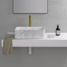 a white sink sitting on top of a counter next to a bottle of soap and a mirror