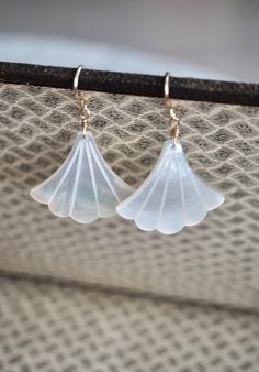 Beautiful and feminine Art Deco fan-shaped white mother of pearl earrings. The pearl has an incredible sheen and take on a subtle glow when they catch the light. They are finished with 14 k gold filled, 14 k rose gold or sterling silver simple earwires. Simple and elegant, you will not go unnoticed. The perfect earrings for a gift or to treat yourself. Ideal for a wedding, and bridesmaids. Made using the highest quality USA and UK sourced materials. *Remember photo can make pieces look larger, please see the "DETAILS" for measurements. Please note that as this is a natural stone, each stone is unique and has its own individual characteristics.  All stones are selected individually and are matched by hand. Natural variations in size, color, cut and clarity are typical and add to the unique Pearl White Mother Of Pearl Wedding Earrings, Wedding Pearl White Mother Of Pearl Earrings, Handmade Mother Of Pearl Earrings For Wedding, Mother Of Pearl Earrings For Wedding, Wedding Pearl Drop Earrings In Shell Shape, Formal Pearl White Mother Of Pearl Earrings, Wedding Mother Of Pearl Drop Earrings, Elegant Shell-shaped Pearl Earrings, Delicate White Pearl Pierced Earrings