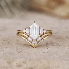 a gold ring with an emerald cut diamond surrounded by three smaller round diamonds on top