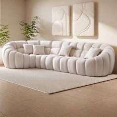 a white couch sitting on top of a hard wood floor next to a potted plant