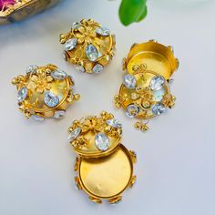 four pieces of gold jewelry sitting on top of a white table next to a flower