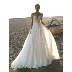 a woman standing on top of a sandy beach next to the ocean wearing a wedding dress