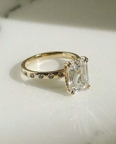 a close up of a ring with a diamond on the front and side, sitting on a white surface