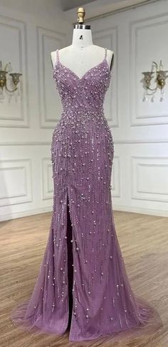 Elegance meets sophistication in our Lavender Sleeveless Pearl and Bead Embellished Front Slit Gown. This exquisite, one-of-a-kind design is perfect for making a statement at any special occasion. The delicate blend of lavender hue, intricate pearl and bead embellishments, and flowing silhouette come together to create a truly show-stopping look. Whether you're walking the red carpet or dancing the night away, our gown is sure to turn heads and make you feel like a vision of beauty. Production t Beautiful Prom Dresses Purple, Lavender Rhinestone Dress, Purple Prom Dress Flowy, Light Purple Prom Dress Lavender, Lilac Evening Gown, Purple Grad Dresses, Pearl Prom Dress, Sparkly Purple Dress, Lavender Ball Gown