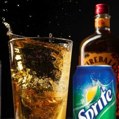 a glass filled with ice and water next to a bottle of sprite soda on top of a table