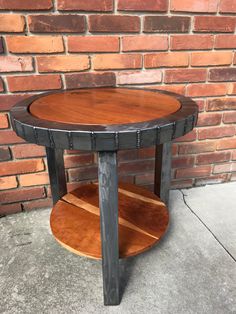 a round wooden table sitting on top of a cement floor next to a brick wall