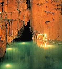 the water is very clear and green in this cave with some lights shining on it