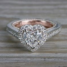 a heart shaped diamond engagement ring on top of a wooden table with wood flooring