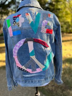 the back of a jean jacket with patchwork and patches on it, sitting on a stand