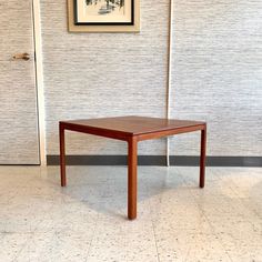 a wooden table sitting in front of a wall with a painting on it's side