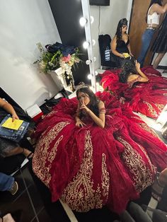 a woman in a red dress sitting on a bed with her reflection in the mirror