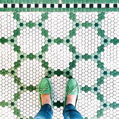 a person wearing green shoes standing on a tiled floor