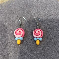 a pair of pink, yellow and blue lollipop earrings sitting on top of a gray carpet