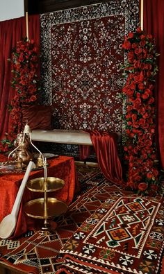 a room with red drapes and rugs on the floor, decorated with flowers