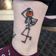 a person with a skeleton tattoo on their leg, holding a jack - o'- lantern