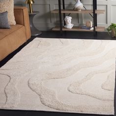 a living room area with a couch, coffee table and rug on the floor in front of it