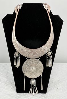 "Vintage Thailand Collar Necklace/Etched Floral/Silver Platted/12\" L x 5 1/2\". Stunning Vintage Hmong Miao Torque silver necklace . Silver plate brass ceremonial Torque Necklace with fringe & bells. Hand engraved with botanical scroll motif & elongated links. Hangs and moves beautifully, the bib fits with hook closure. Good vintage condition, the few areas that are showing age are some of the silver around the neck area is faded and the two top dangling flowers are pushed in. Please see pictures for full details. Miao silver is not pure silver, but an alloy of silver, copper and nickel. It's a traditional material for making jewelry by craftsmen of Miao Hmong ethnic tribe. Necklace hangs: 12\" long x 5 1/2\" wide" Artisan Silver Etched Necklace, Adjustable Silver Ceremonial Necklace, Silver Adjustable Necklaces For Ceremonial Occasions, Silver Adjustable Necklace For Ceremonial Use, Adjustable Silver Necklace For Ceremonial Use, Adjustable Silver Necklace For Ceremonial Occasions, Ceremonial Silver Medallion Necklace, Silver Medallion Necklace For Ceremonial, Silver Medallion Necklace For Ceremonial Occasions