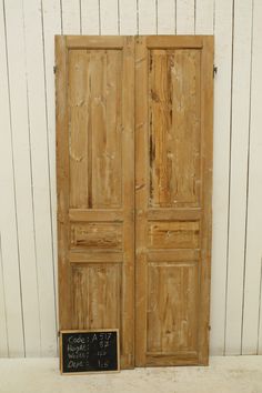 an old pair of wooden doors with chalkboard on the bottom and bottom, against a white wall