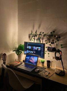 a laptop computer sitting on top of a wooden desk next to a potted plant