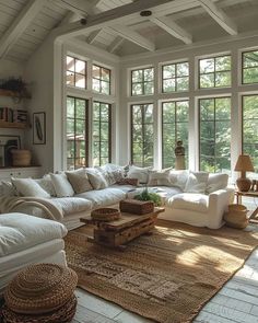 a living room filled with lots of white furniture and large windows above the couches