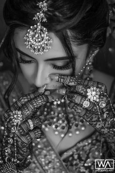 a woman with her hands on her face and jewelry around her neck, in black and white