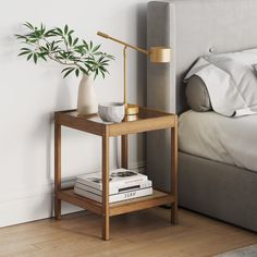 a bedroom with a bed, nightstand and plant on the side table next to it