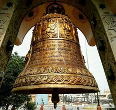 a large golden bell hanging from the side of a building