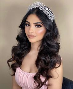 a woman wearing a tiara with long dark hair and blue eyeshadow is posing for the camera