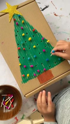 a child is painting a christmas tree on a cardboard box with crayons and colored pencils