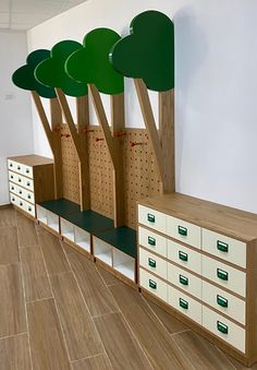 an empty room with many drawers and green trees on the wall above them, in front of a white wall