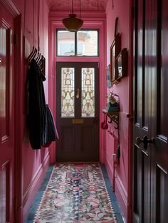 the hallway is painted bright pink and has an ornate tile floor with colorful designs on it