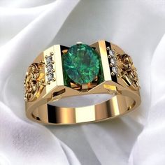 a gold ring with a green stone surrounded by white and yellow diamonds on a white cloth