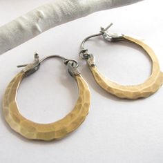 "Small handcrafted forged bronze hoops with sterling silver ear wires. Artfully hammered for dynamic texture and fitted with 20 gauge ( standard size) sterling silver ear wires with a secure and easy to use friction clasp. Lightweight at less than 4 grams each.A perfect pair for any time, anywhere! 1 and 1/8\" wide or 2.66cm and apx. 1.25\" tall or 3.1cm. If you would prefer a slighter thicker (18 gauge) ear wire please let us know in notes to seller at the time of purchase. The pair pictured ha Unique Hammered Hoop Earrings Gift, Bronze Hoop Earrings Hand Forged, Artisan Bronze Nickel-free Hoop Earrings, Small Hoop Hammered Brass Jewelry, Artisan Electroformed Hoop Earrings, Small Hoop Brass Earrings With Hammered Detail, Small Hoop Hammered Brass Earrings, Hand Forged Bronze Hoop Earrings For Gift, Everyday Hand Forged Bronze Earrings