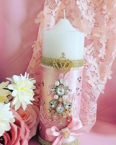 a pink candle is sitting next to some flowers and laces on a pink background