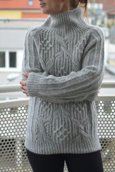 a woman in grey sweater and black leggings posing for the camera with her arms crossed