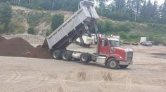 a dump truck is dumping dirt on the road