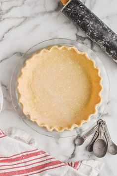 an uncooked pie sitting on top of a table next to utensils