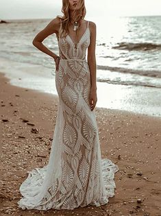 a woman standing on top of a sandy beach next to the ocean wearing a dress