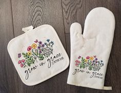 two oven mitts with embroidered words on them sitting on a wooden floor next to each other