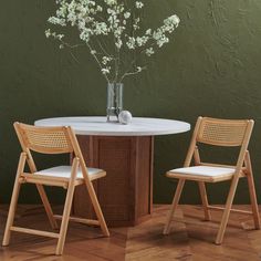 two chairs and a table with flowers in a vase