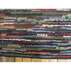 a multicolored area rug is shown on a wooden floor with wood planks in the background